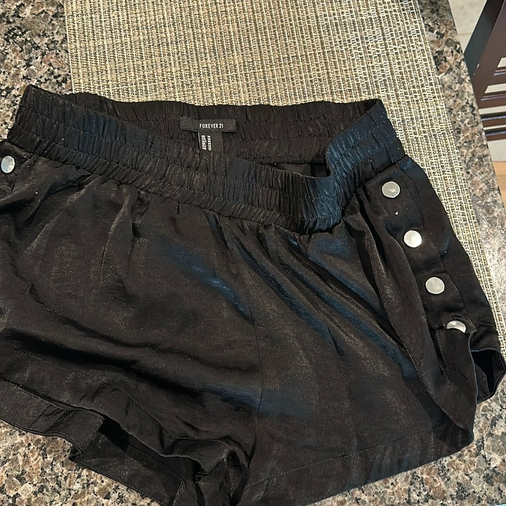 Black satin shorts with metal buttons on both sides